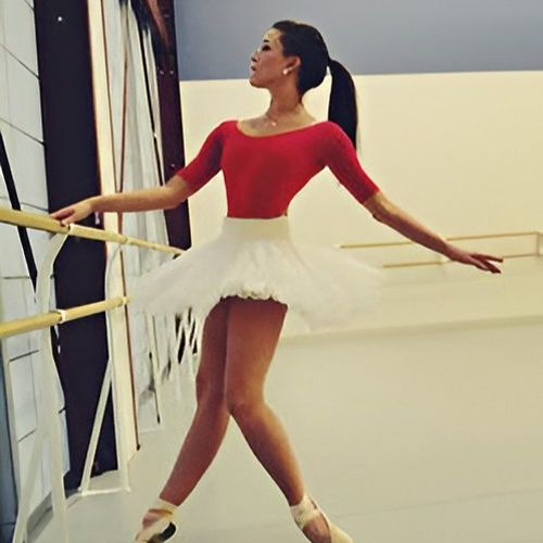 Ballet dancer in red practicing at barre.