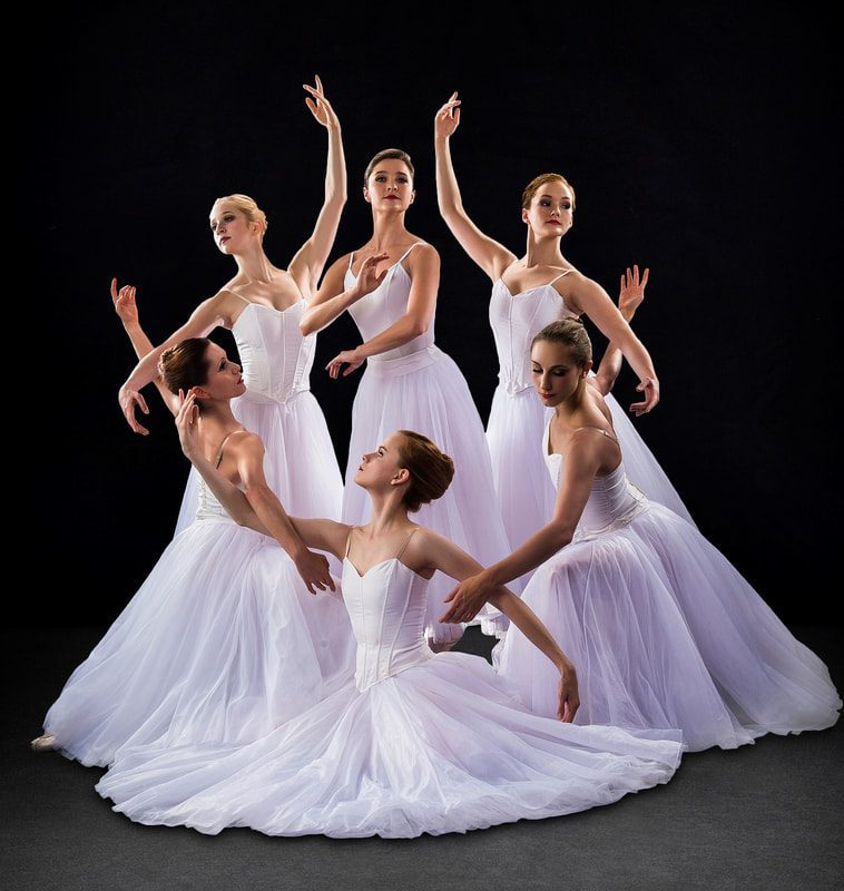 Ballet dancers posing in elegant white dresses.