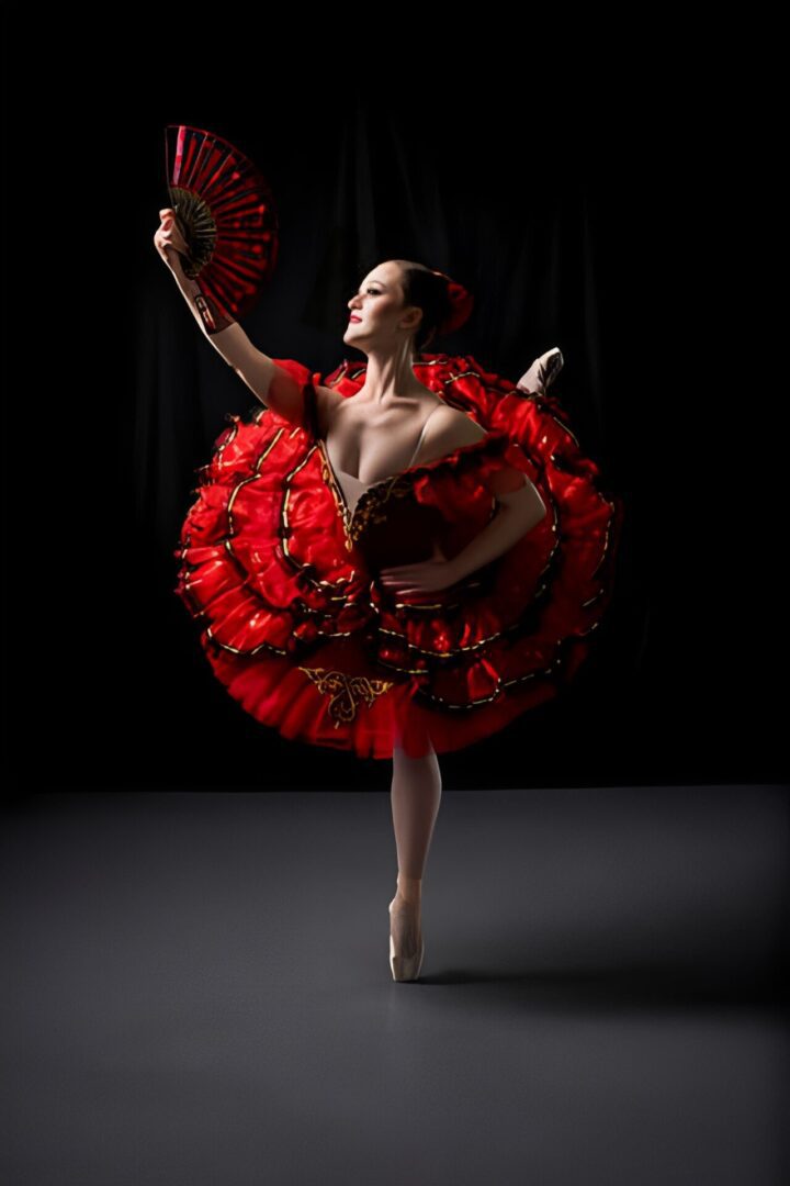 Ballet dancer in red costume, holding fan.