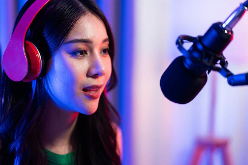 Podcaster with pink headphones speaking into microphone